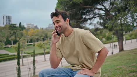 hombre feliz marca el número de teléfono relajándose en el banco de la calle de cerca. tipo comenzar a llamar