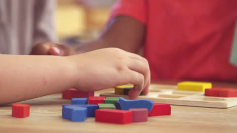 maestro y alumnos usando formas de madera en la escuela montessori