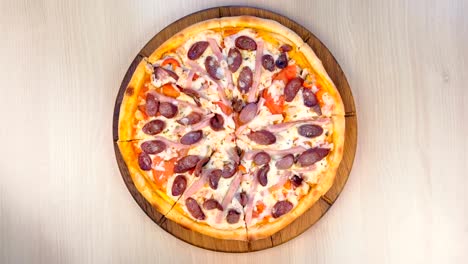 cortando pizza con salchichas ahumadas, jamón y queso.