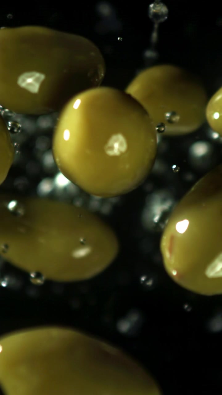 Super rallentatore di gocce d'acqua che schizzano su olive verdi