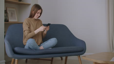 mujer de negocios escribiendo un mensaje en el teléfono móvil en la oficina de casa. chica joven hablando por teléfono en cámara lenta. cerca de manos de mujer joven usando teléfono inteligente en el sofá.