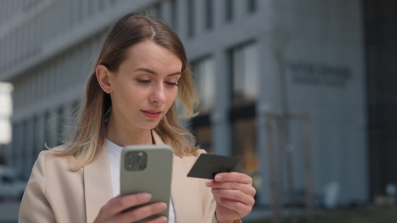 Giovane donna che effettua un pagamento online con smartphone e carta di credito.