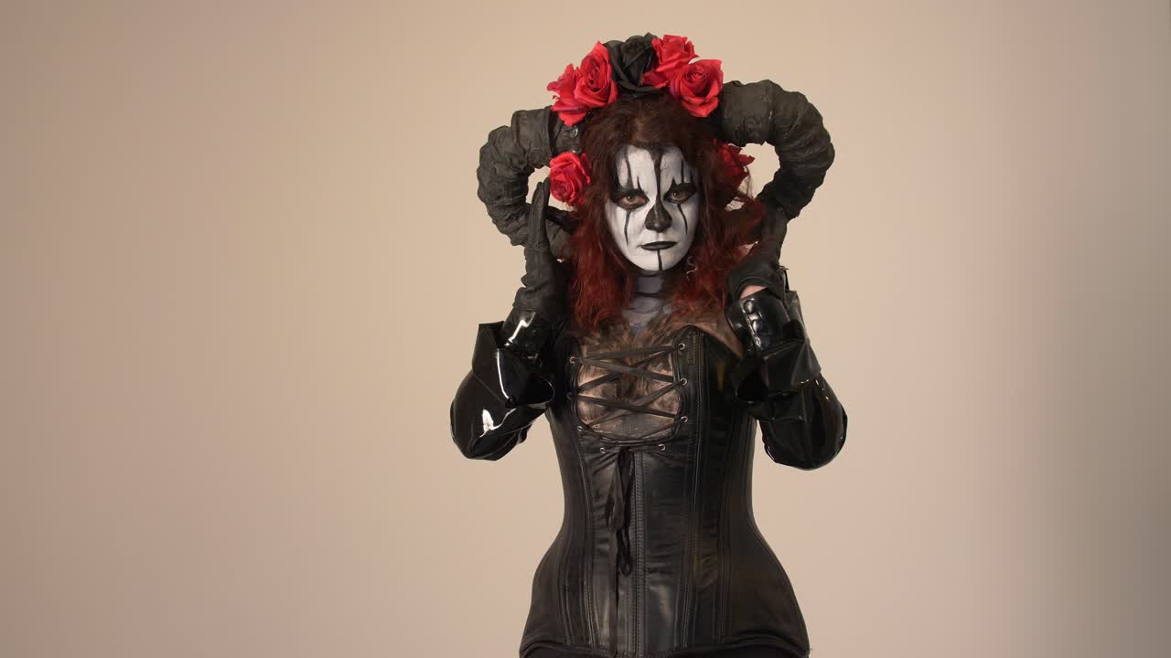 Gotisk kvinne med djevelhorn og roser i Halloween-kostyme
