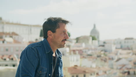 side view of smiling male person looking at landscape of big city