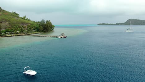 panning from drone of bora bora lagoon looking out to the reef of blue and turquoise