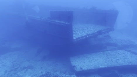 Cinematic wide shot from a submarine porthole going around the end of a shipwreck on the ocean floor off the coast of the Big Island of Hawai&#039;i