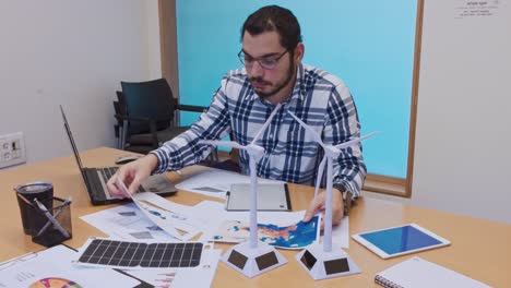 man working on renewable energy models and plans in an office setting
