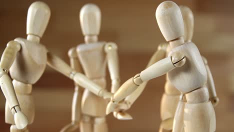 wooden figurines representing businesspeople forming a handstack