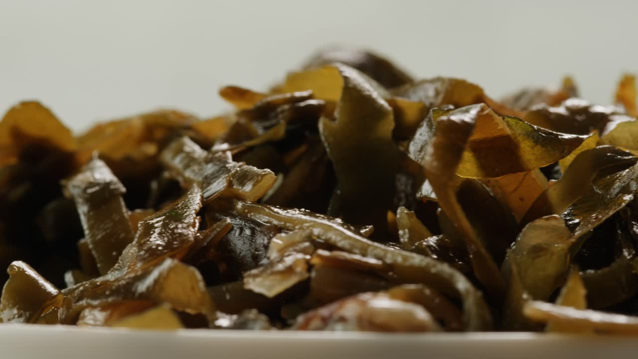 Japanese wakame sea weed laminaria chuka fermented food. Close-up on a detail of Hiyashi Wakame Chuka or seaweed salad or seaweed with sesame seeds on a plate. Top view. Seafood background.
