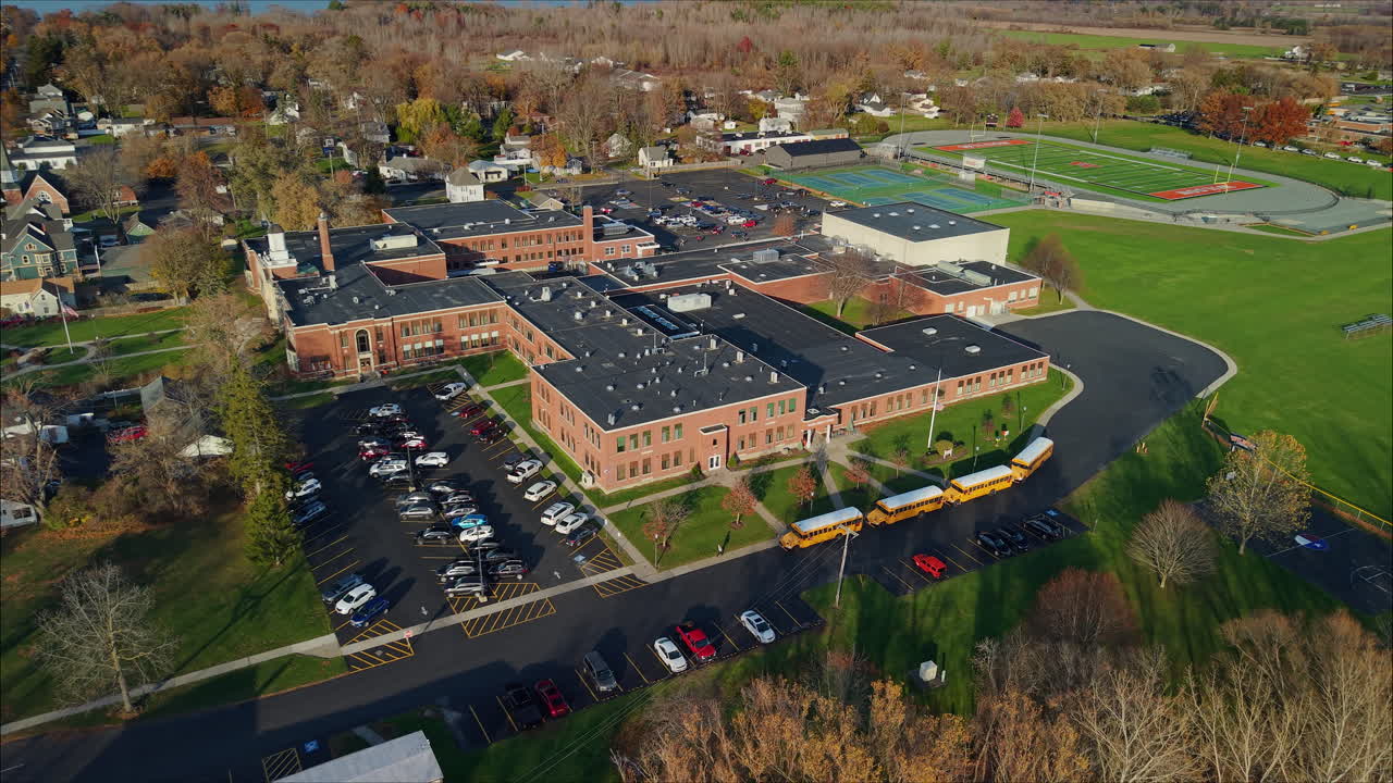 Aerial view of a school building with a parking lot and football field