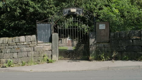 cemetery gates in high summer, gravestones and trees in yorkshire, uk