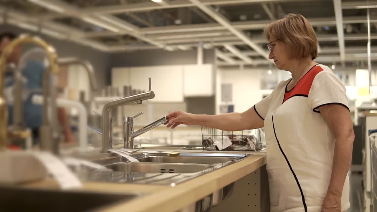 mujer comprando fregadero de cocina y grifo en una tienda de muebles