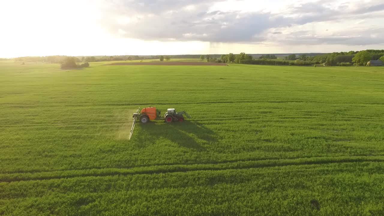 Pesticide and fertilizer spraying on the field aerial view with tractor