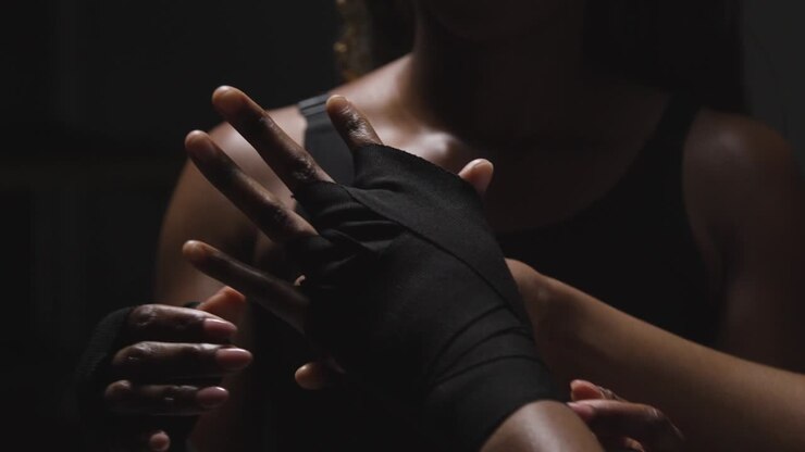 Scatto in studio di donne che si mettono le fasce da boxe sulle mani prima di allenarsi insieme 3