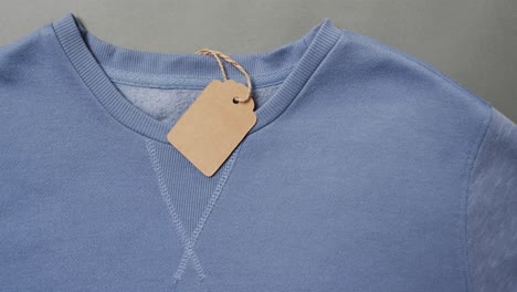 Video-of-flat-lay-of-blue-t-shirt-with-tag-and-copy-space-on-grey-background