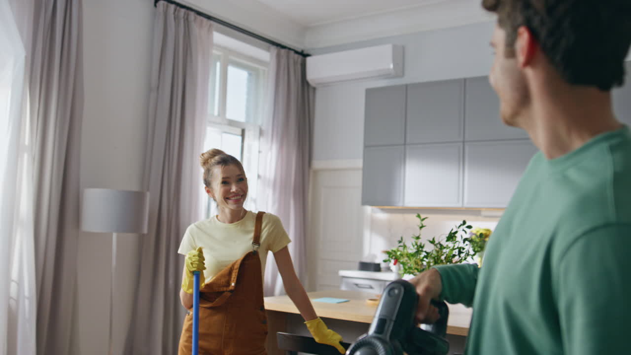 Cleaning house couple laughing closeup. Lady using floor mop talking to husband