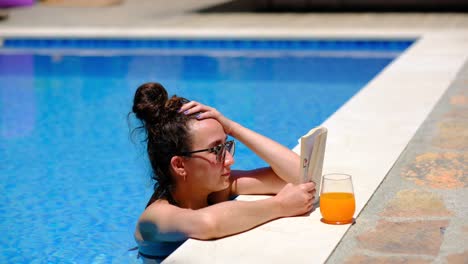 Una-Mujer-Leyendo-Un-Libro-En-La-Piscina