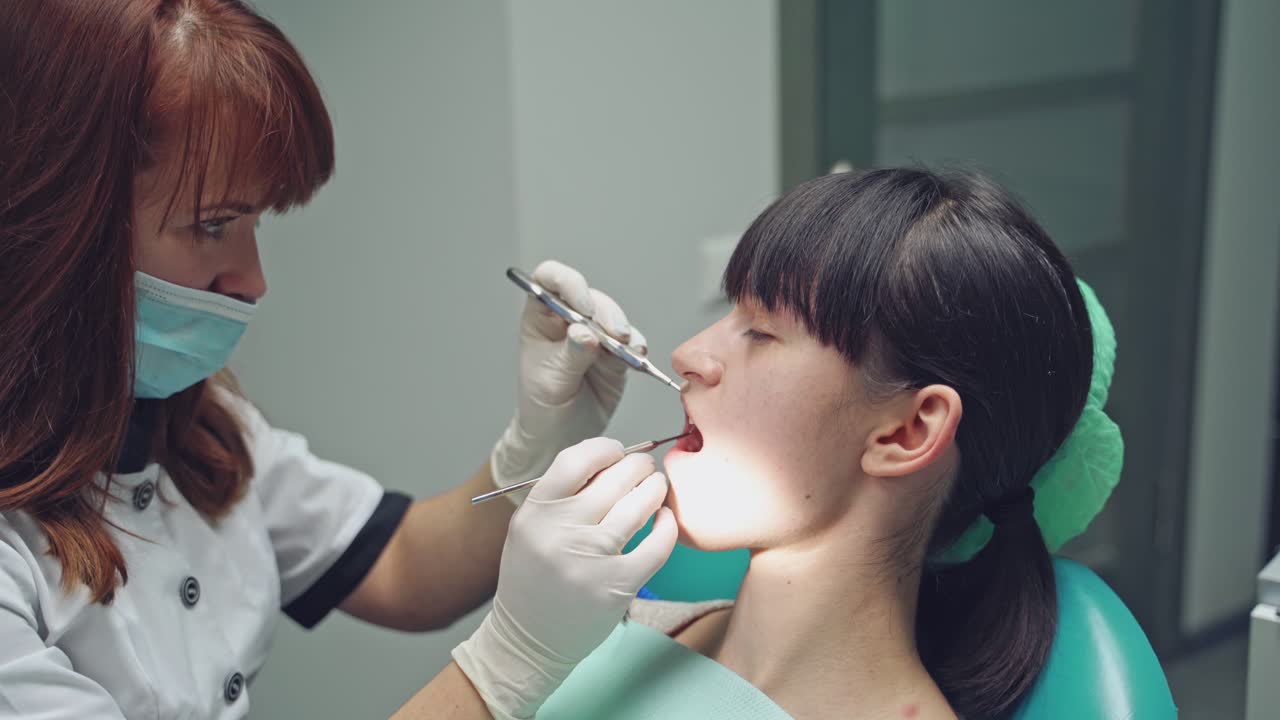 Dental clinic. Reception, examination of the patient. Teeth care. Young girl undergoes a dental examination by a dentist