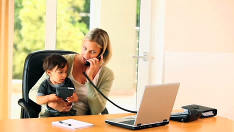 mother doing office work with baby on her lap