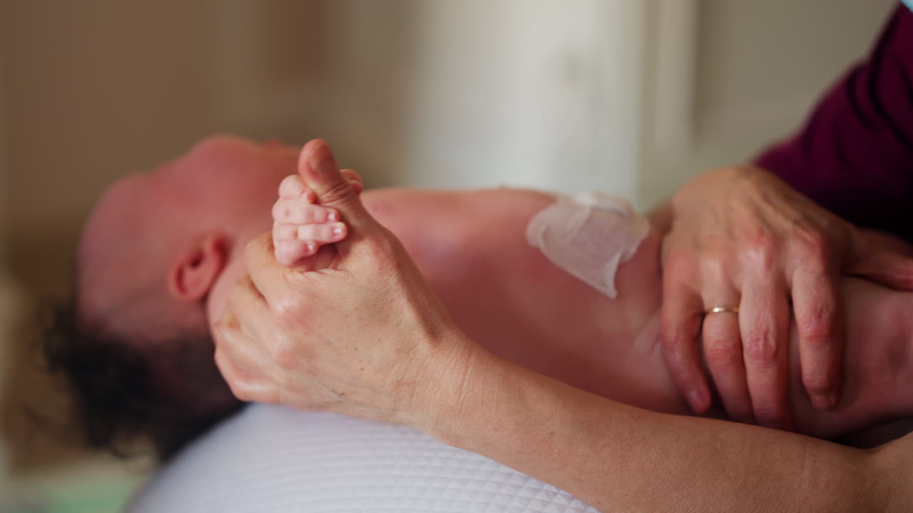 Baby placed on a stability ball while adults support the infant's body