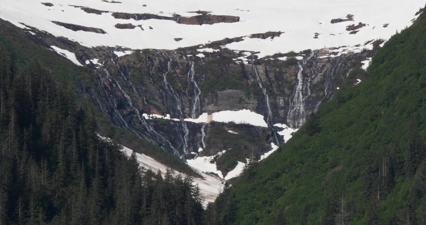 Aljašská krajina se zasněženými horami a nedotčenými vodopády za slunečného letního dne ve fjordu Endicott Arm.