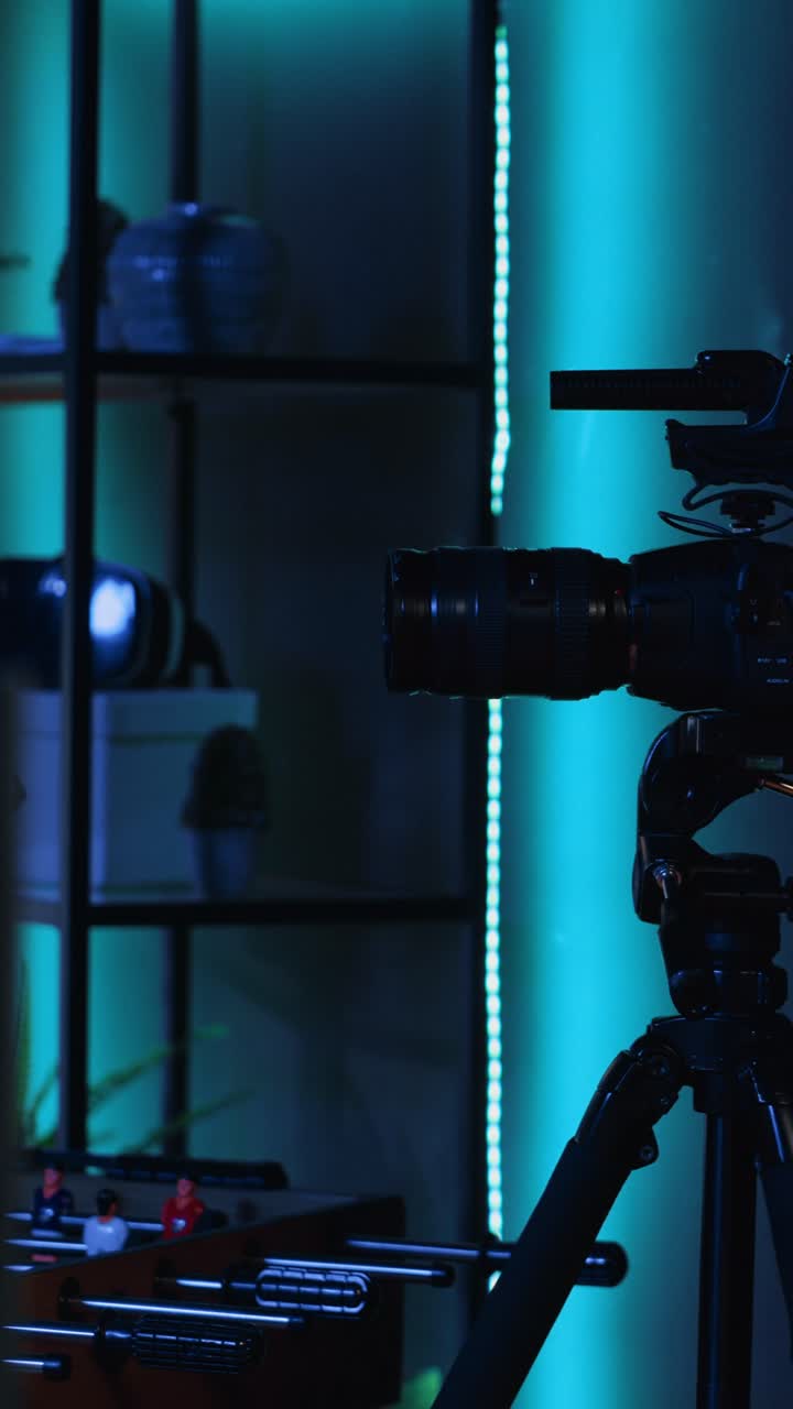 Vídeo vertical. Equipamento de câmera profissional em estúdio de fotografia criativa vazio com iluminação neon azul
