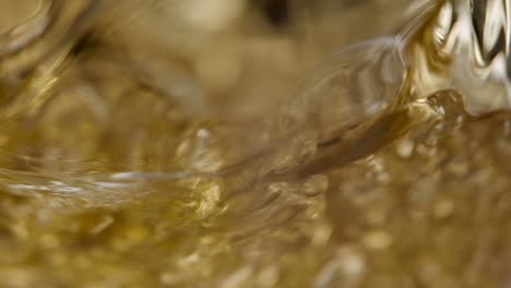 golden liquid being poured into a glass super slowmotion