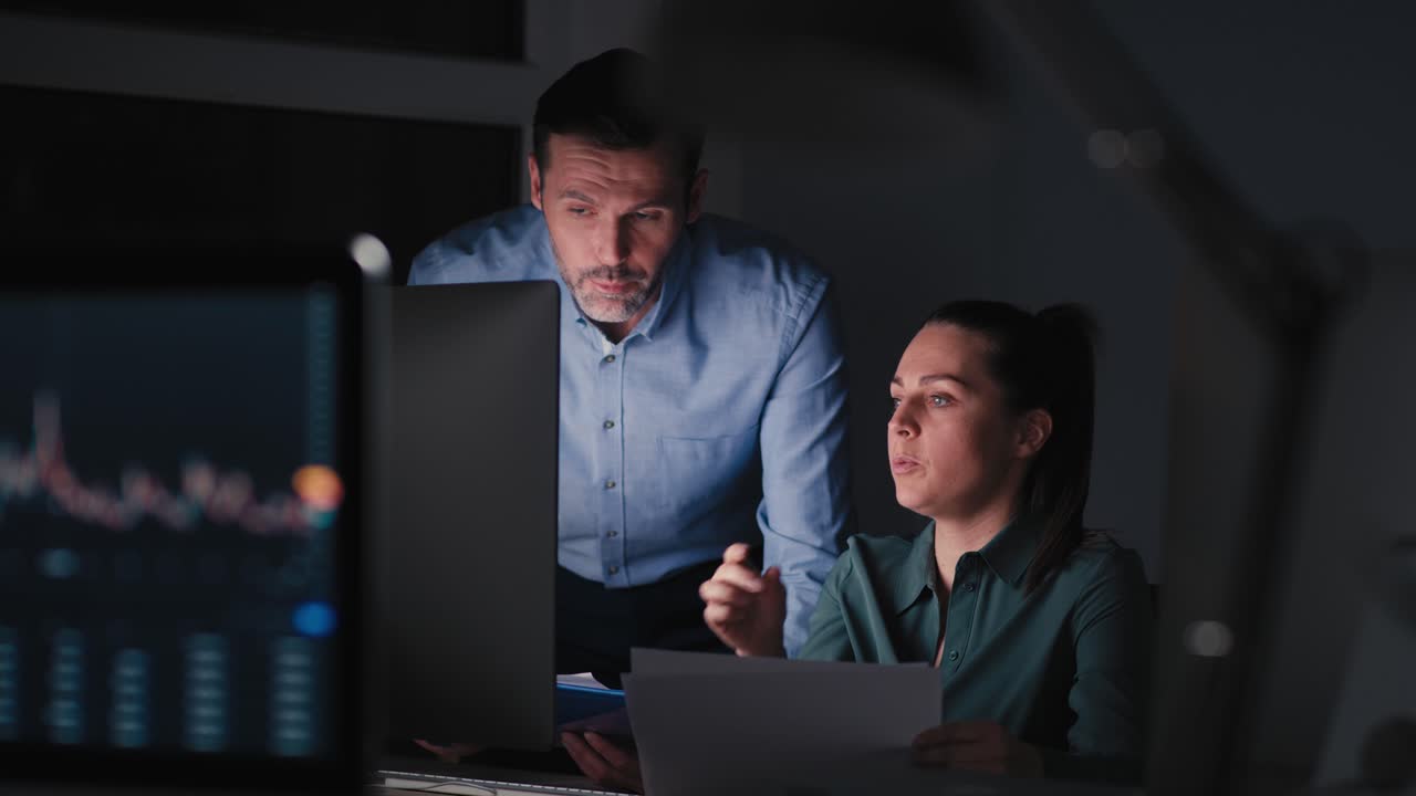 mujer y hombre caucásicos trabajando hasta tarde juntos en la oficina