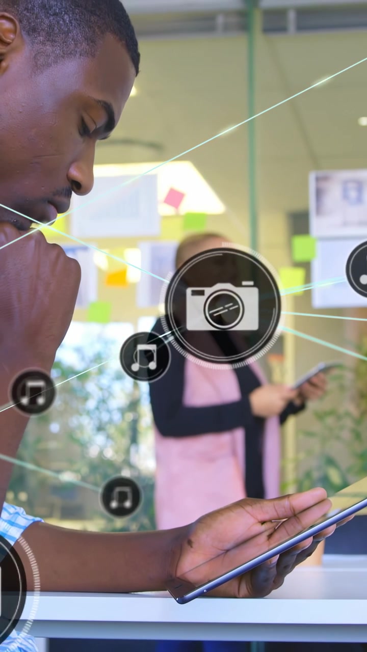 Vertical video: Man tapping tablet, spawning icons and lines across glass, showing business network