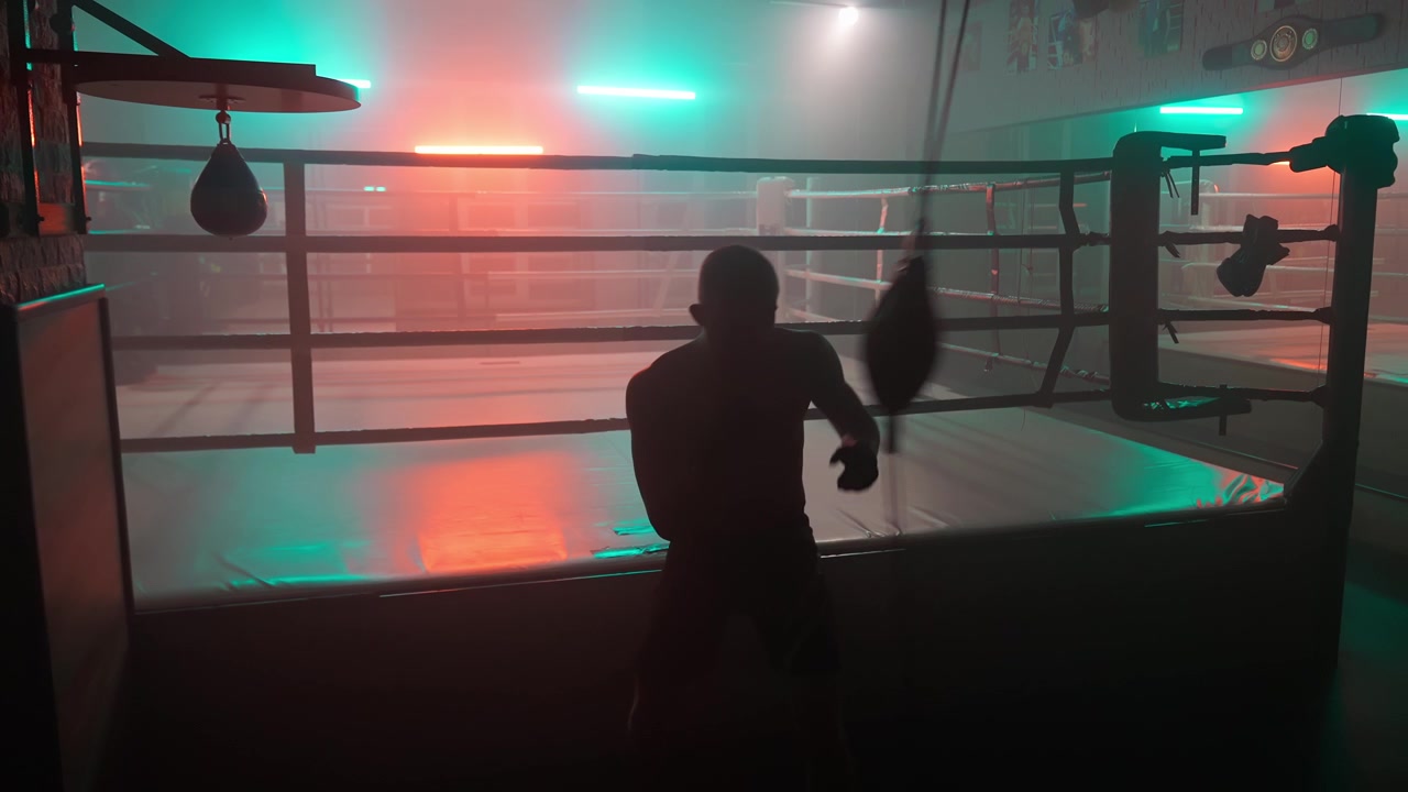 Silhouette di un pugile che si allena con il sacco veloce in una palestra buia con luci al neon