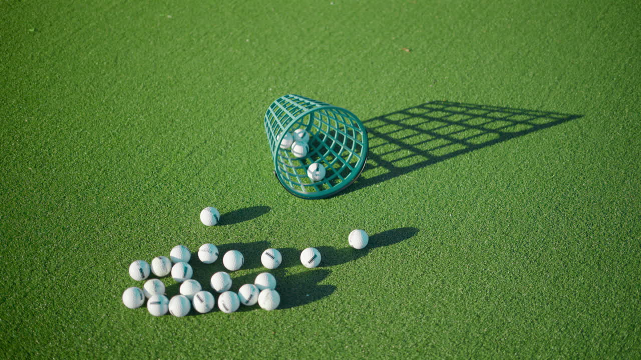 Diverse palline da golf vicino a un secchio verde su un campo, in una giornata di sole