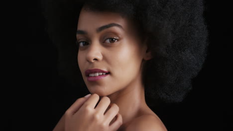 portrait attractive african american woman touching face with hands caressing smooth healthy skin complexion enjoying perfect natural beauty funky afro on black background