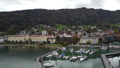 Vista-Aérea-De-La-Histórica-Ciudad-De-Bregenz-A-Orillas-Del-Lago-De-Constanza-En-Un-Feliz-Día-Nublado-De-Otoño-Rodeado-De-Colinas-Y-Con-Los-Barcos-En-El-Puerto,-Sin-Gente,-Vorarlberg,-Austria,-Europa