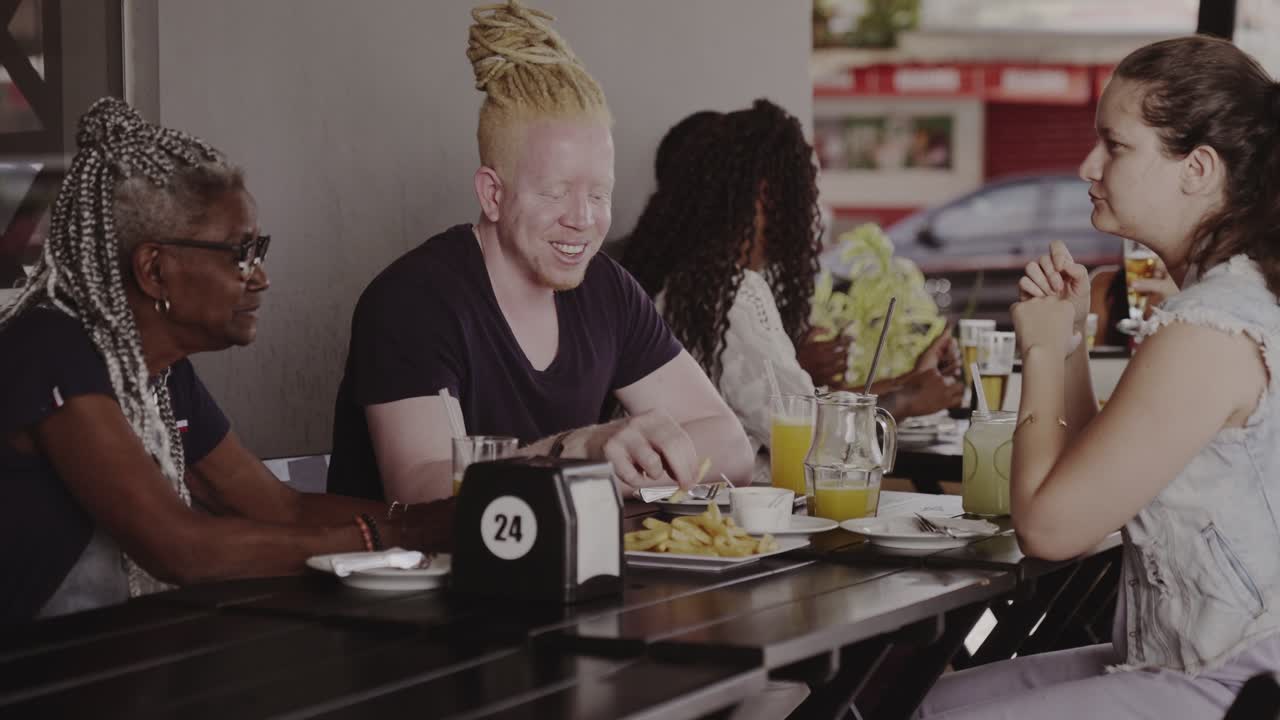 A diverse group of friends enjoying a meal and conversation at an outdoor cafe