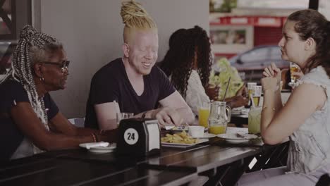 a diverse group of friends enjoying a meal and conversation at an outdoor cafe