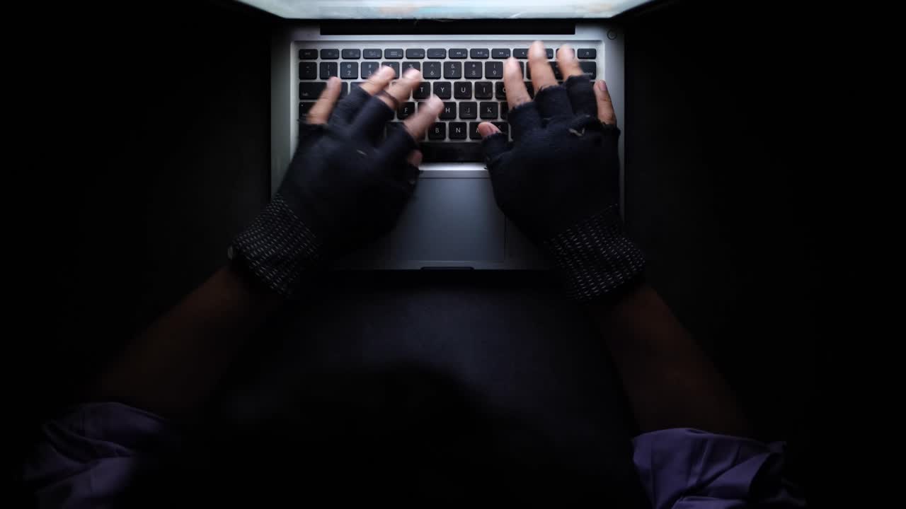 밤에 장갑을 착용하여 노트북으로 타이핑하는 사람