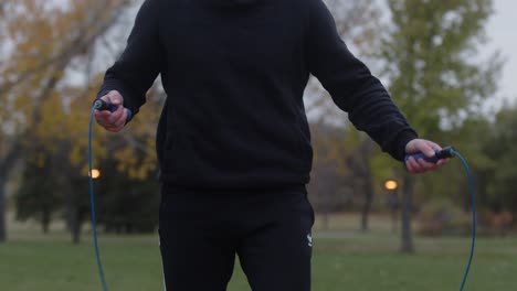 Athletic-man-jumping-rope-in-a-park-at-dusk-for-training