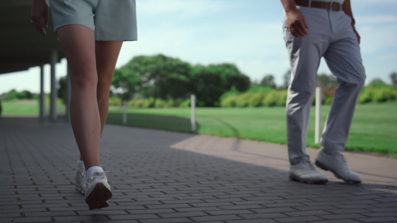 골프 전문가 들 은 잔디 코스 에서 함께  ⁇ 고 있다. 두 다리 가 골프 카트 를 타고 있다