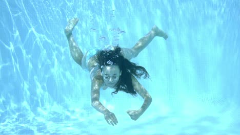 chica nadando bajo el agua en una piscina