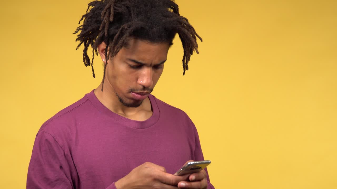 A thoughtful young black male nervously scrolling his phone