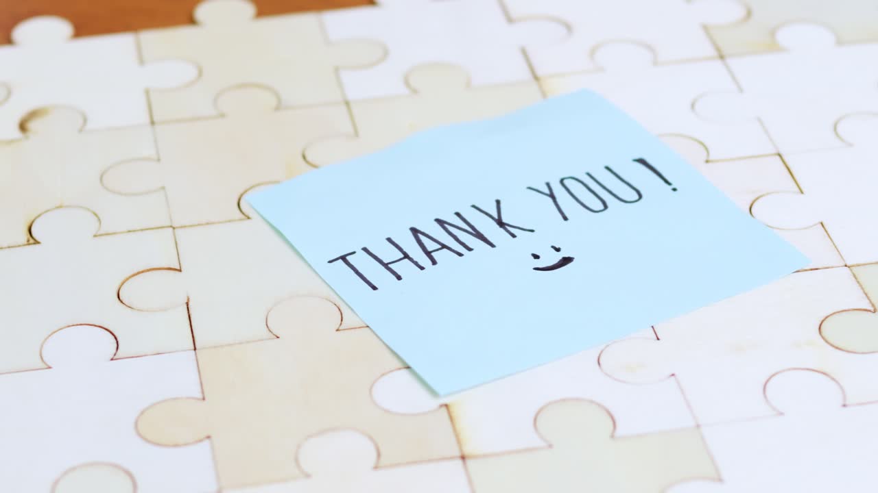 A close-up view of a hand placing a piece a puzzle with a thank you note symbolizing completion and gratitude