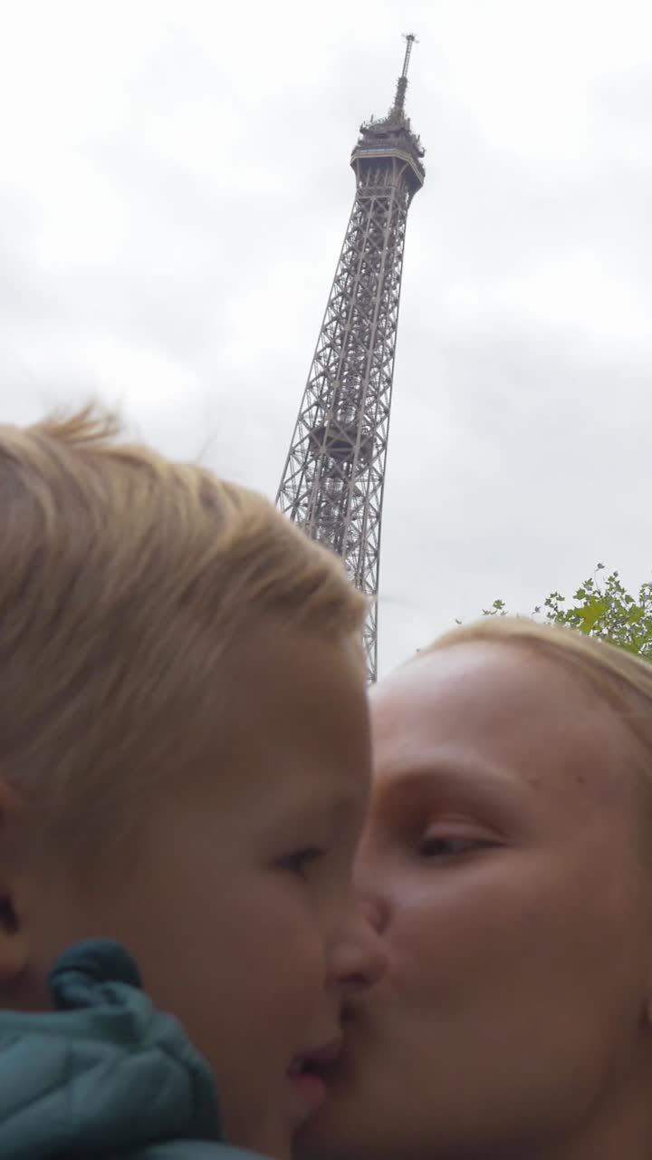 Madre e figlio felici che si baciano davanti alla Torre Eiffel.