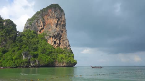 playa de railay tailandia acantilados de piedra caliza con barco de cola larga y nubes de tormenta