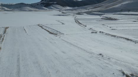 a drone footage over castelluccio - italy during winter period with snow
