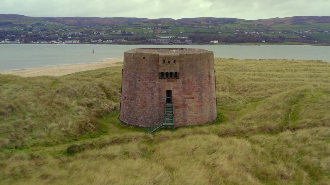 Luftoptagelse med tilbagetrækning og opstigning fra Magilligan Martello Tårnet, der afslører Lough Foyle og det naturskønne Donegal-landskab.