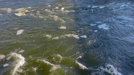 Kühler-Bach-Mit-Schwimmenden-Eisschollen,-Sonnenlicht-Spiegelt-Sich-Im-Wasser