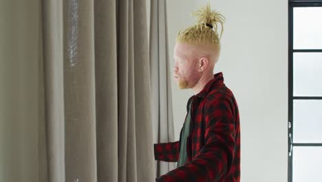 thoughtful albino african american man with dreadlocks looking at the window