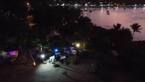 Strandbar-Am-Meer-Bei-Sonnenuntergang-Bunte-Lichter-Mit-Drohne,-Palmen-Und-Weißem-Sand