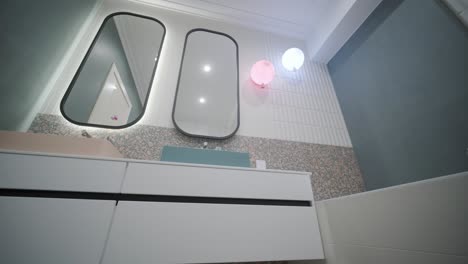 baño moderno con espejos redondeados únicos, encimeras de terrazo y luces de pared lúdicas que crean un espacio dinámico y elegante