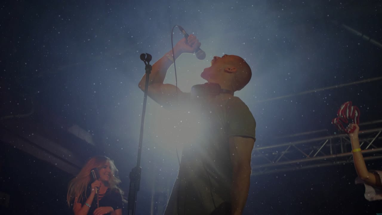 Man lead singer singing on music stage lighting sparking star sparkle overlay shading band for fans